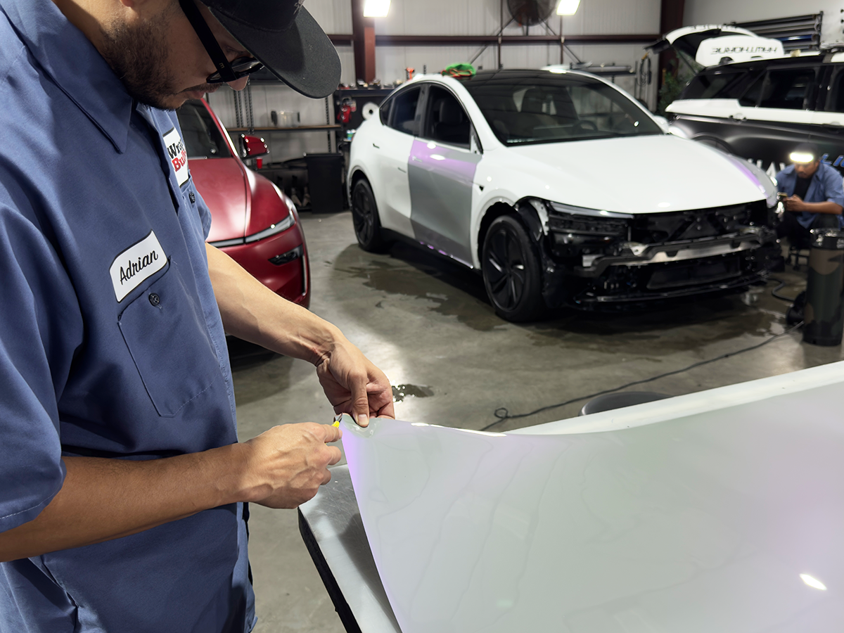 Vehicle wrap technician cutting and preparing wrap material by hand at Wrap Bullys