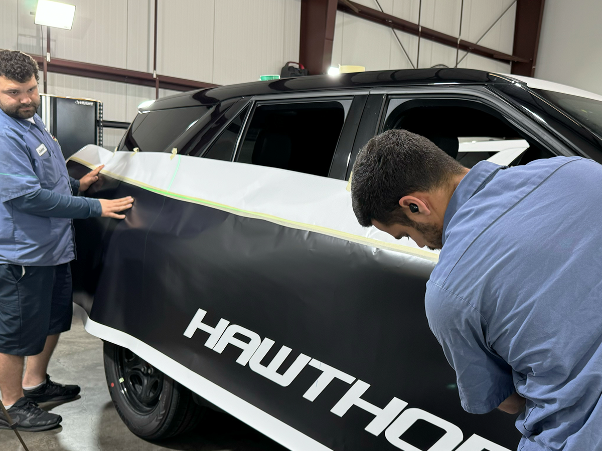 Wrap Bullys technicians laying and positioning commercial wrap material on a vehicle panel