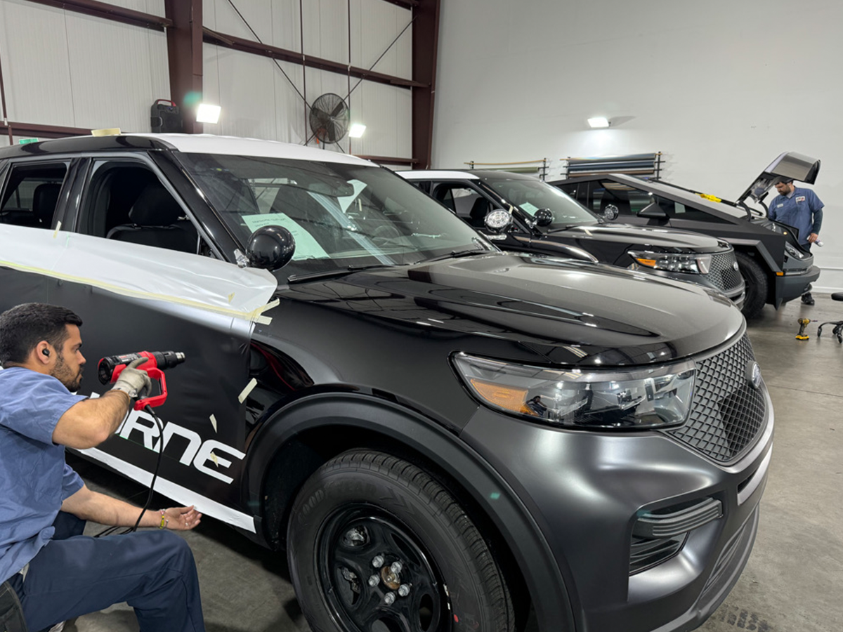 Vehicle wrap technician squeegeeing and finishing commercial wrap material at Wrap Bullys